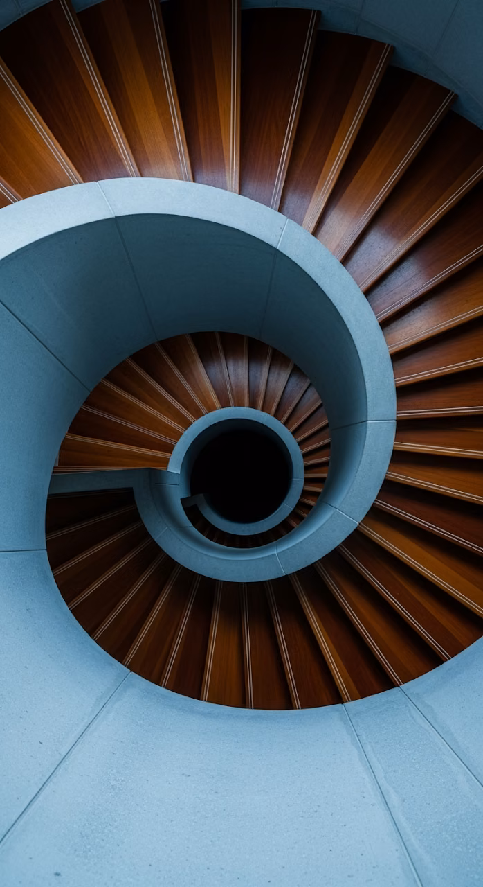 Abstract Top-Down View of a Modern Architectural Spiral Staircase with Wood Treads and Concrete Railing - Free Mobile AMOLED Wallpaper Background