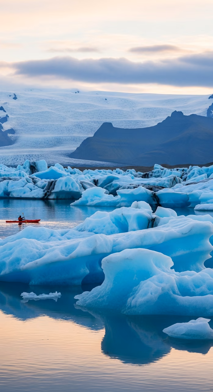 Close-Up Vertical View of Blue Icebergs and Kayaker in Glacial Lagoon at Twilight - Free Mobile AMOLED Wallpaper Background
