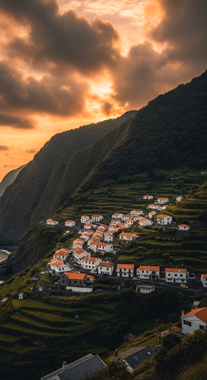 Elevated View of a Coastal Village on a Steep Green Hillside at Sunset - Free Mobile AMOLED Wallpaper Background