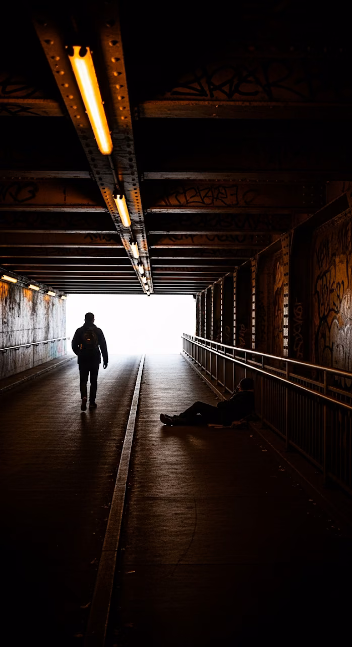 Gritty Low-Key Cinematic Scene of a Man Walking Up a Dark Urban Underpass Ramp with Yellow Lights - Free Mobile AMOLED Wallpaper Background