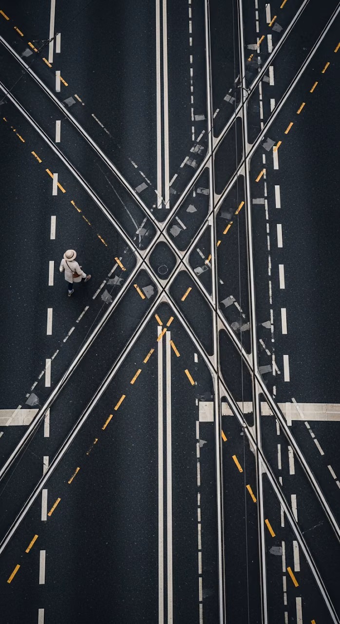 High-Angle Abstract View of a Solitary Pedestrian Walking on Wet Asphalt with Tram Tracks - Free Mobile AMOLED Wallpaper Background