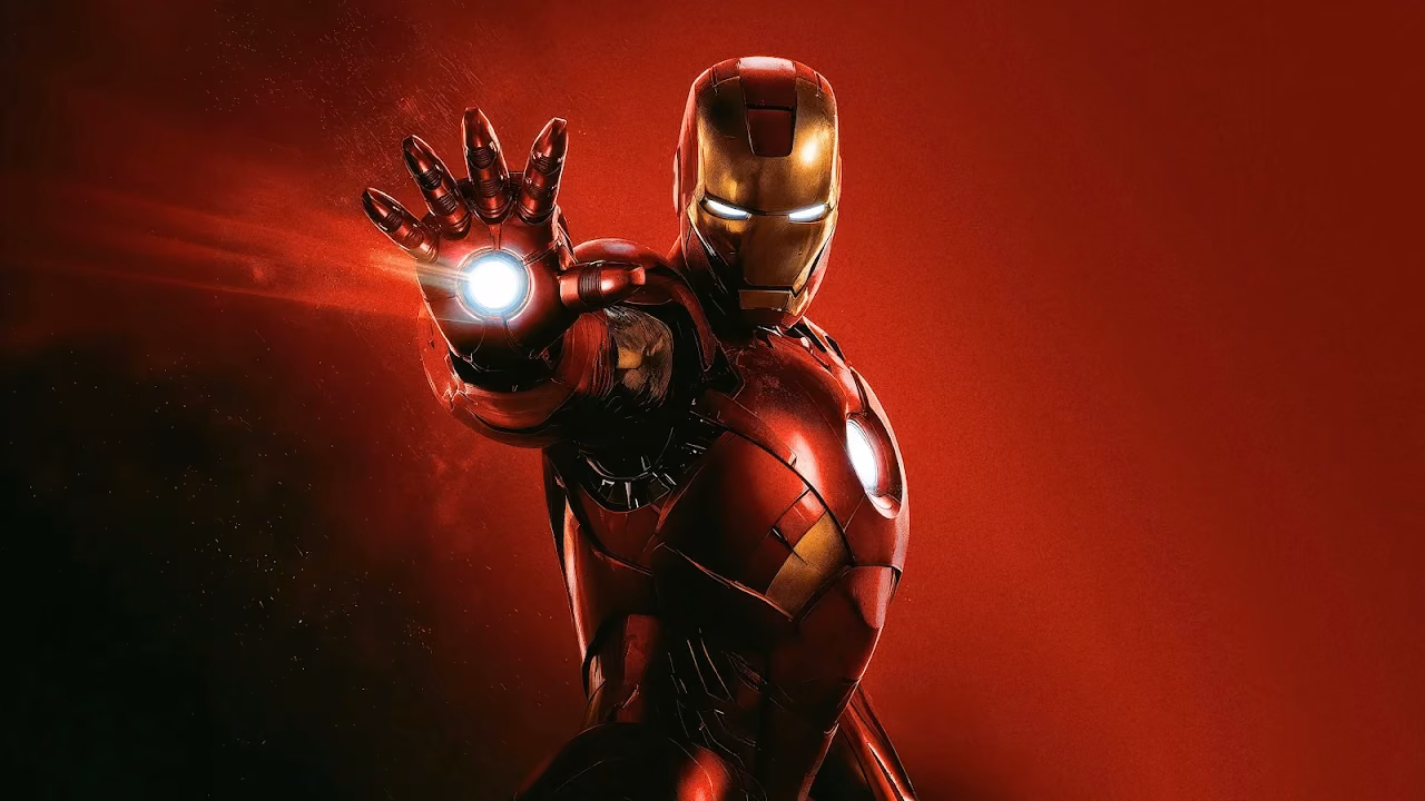 Download Iron Man Repulsor Beam Red Studio 4K Wallpaper in 4K UHD Iron Man in red and gold armor with glowing eyes and chest reactor, aiming a white repulsor hand beam on a red background.
