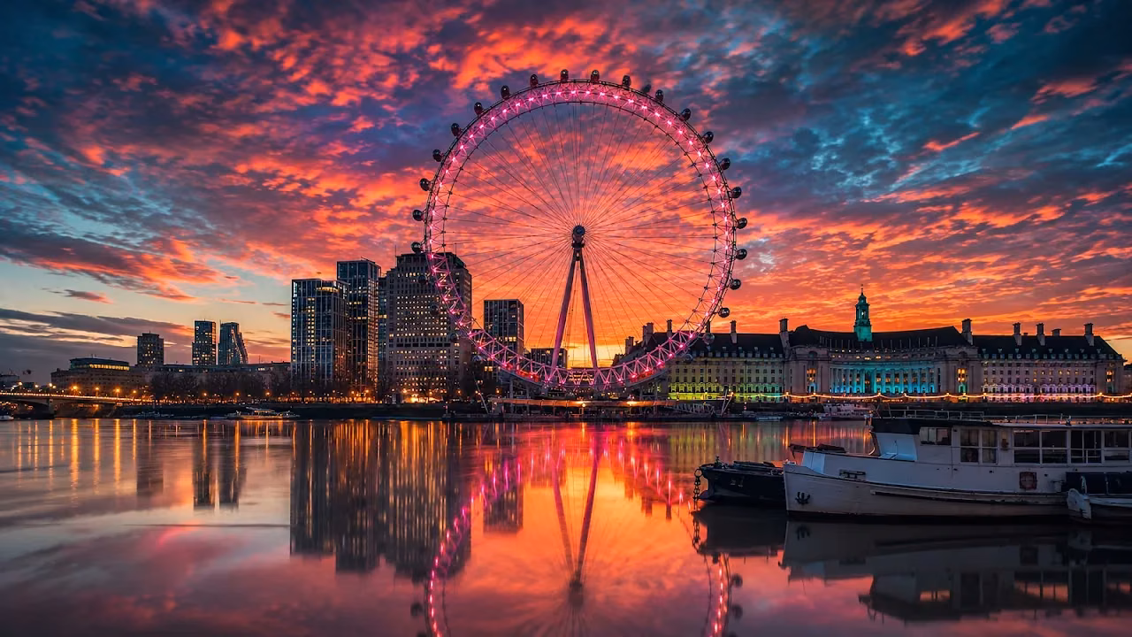 Download London Eye River Thames Sunset Glow 4K Wallpaper in 4K UHD London Eye illuminated in pink, reflecting on the calm River Thames under an orange and purple sunset sky.