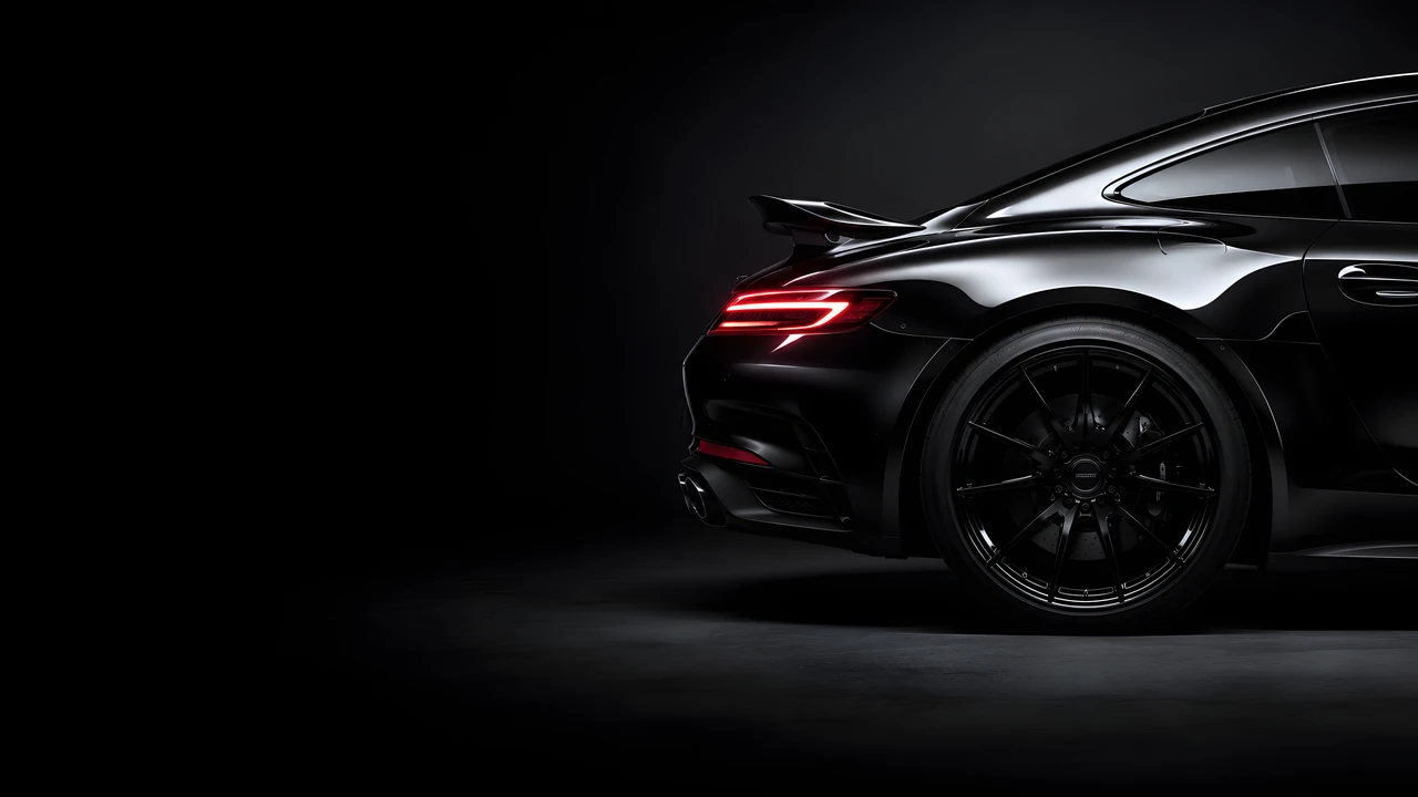 Download Minimalist Black Sports Car Desktop Wallpaper Wallpaper in 4K UHD Glossy black high-end sports car rear quarter panel showcasing curved bodywork and a sleek red light bar against a dark gray backdrop.