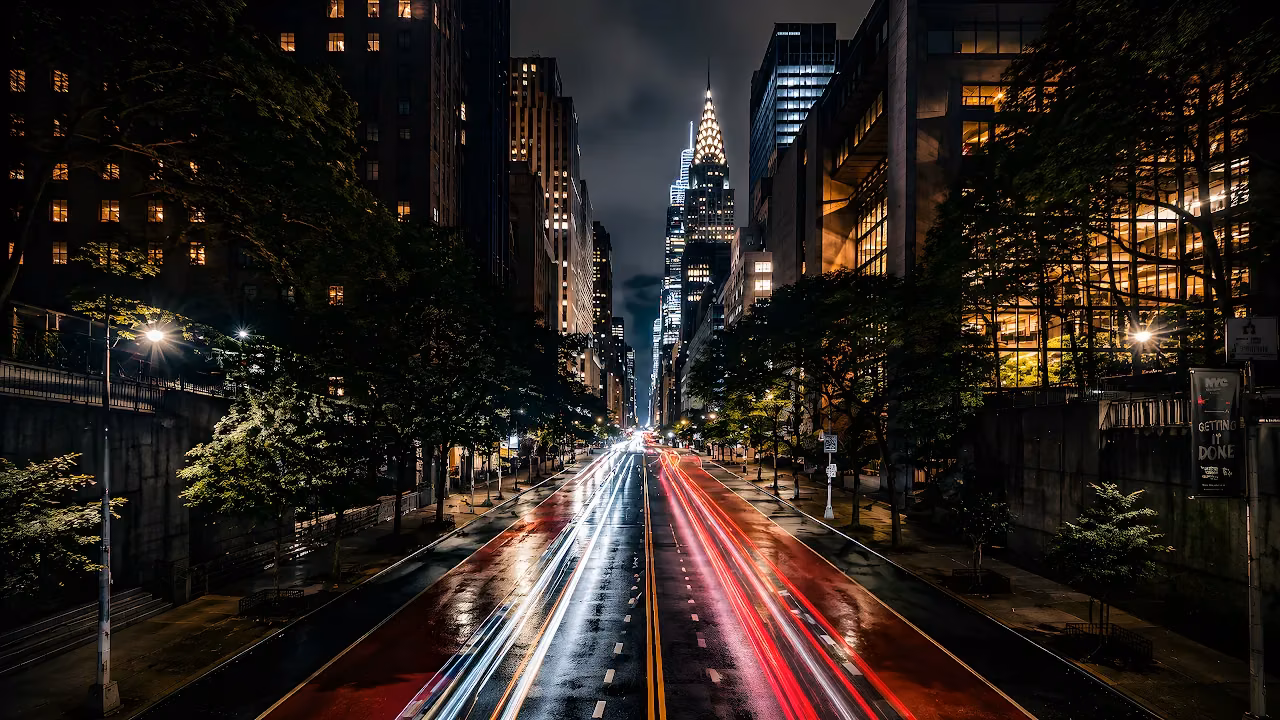Download NYC Chrysler Building Night Traffic 4K Wallpaper in 4K UHD Long exposure photo of red and white car light trails on a New York City street facing the Chrysler Building.