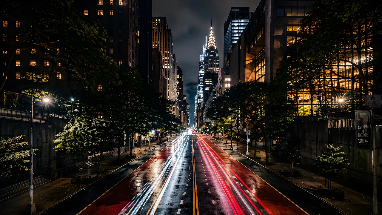 Long exposure photo of red and white car light trails on a New York City street facing the Chrysler Building.