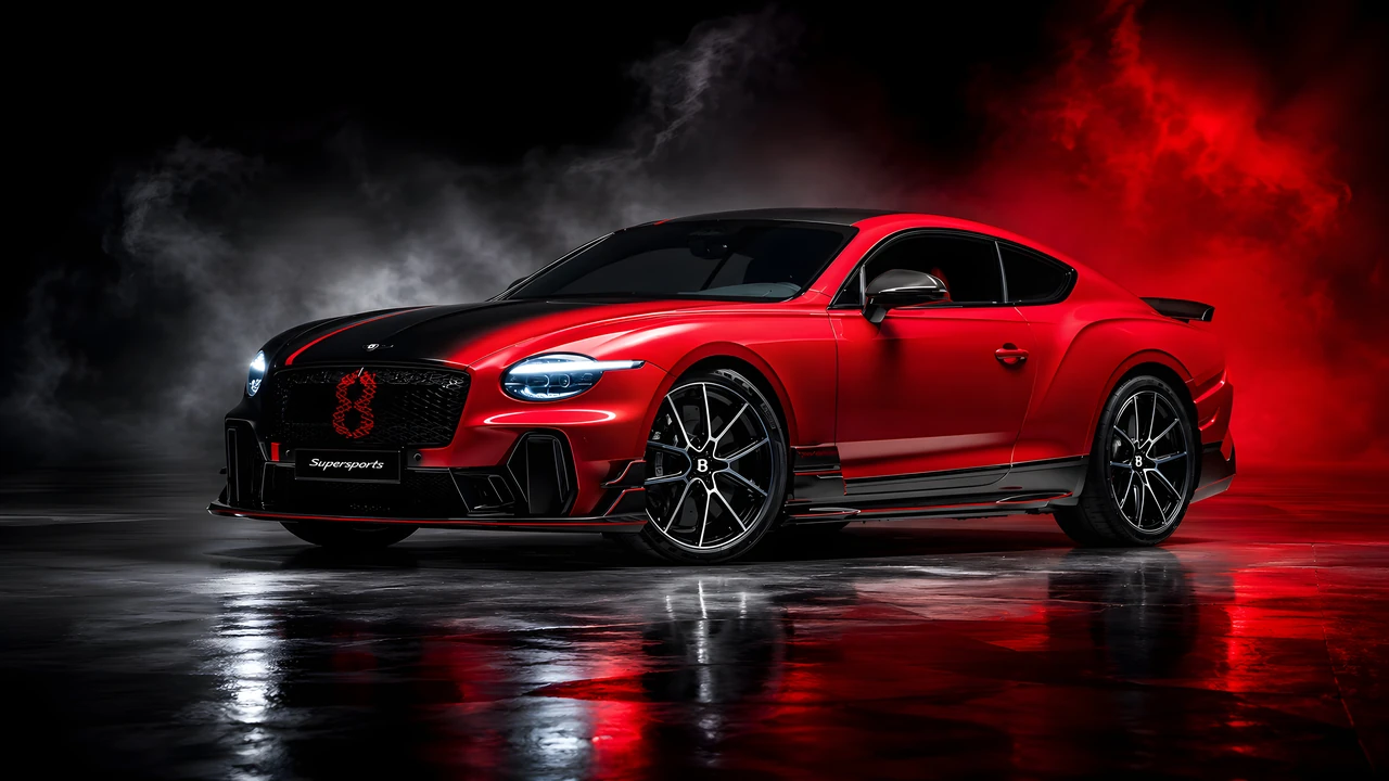 Red and black performance coupe parked on a reflective floor in a dark studio.