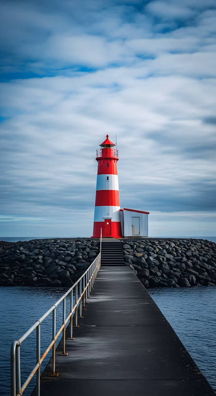 Download Red and White Lighthouse on Rocky Jetty Under Cloudy Sky Wallpaper in Mobile HD Red and White Lighthouse on Rocky Jetty Under Cloudy Sky - Free Mobile AMOLED Wallpaper Background