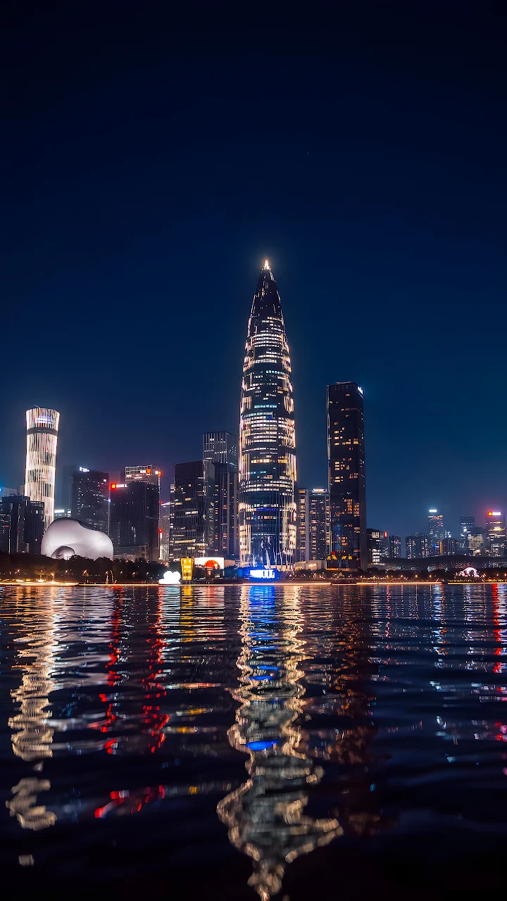 Download Shenzhen Skyline Bay Night Reflection 4K Wallpaper in Mobile HD Shenzhen skyline and illuminated bamboo shoot tower reflecting across water at night.