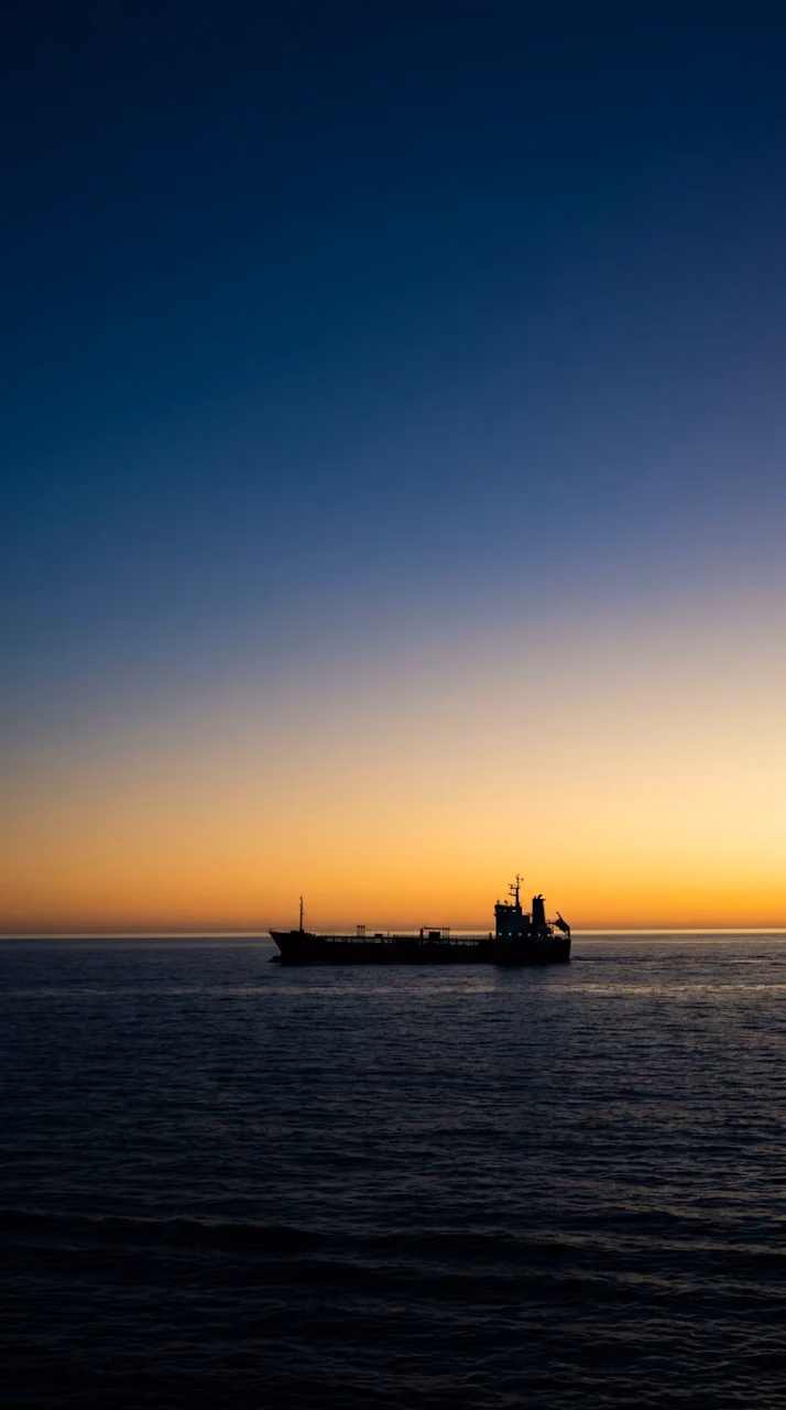 Silhouetted Ship Sailing on Vast Ocean Under Indigo and Gold Sky - Free Mobile AMOLED Wallpaper Background