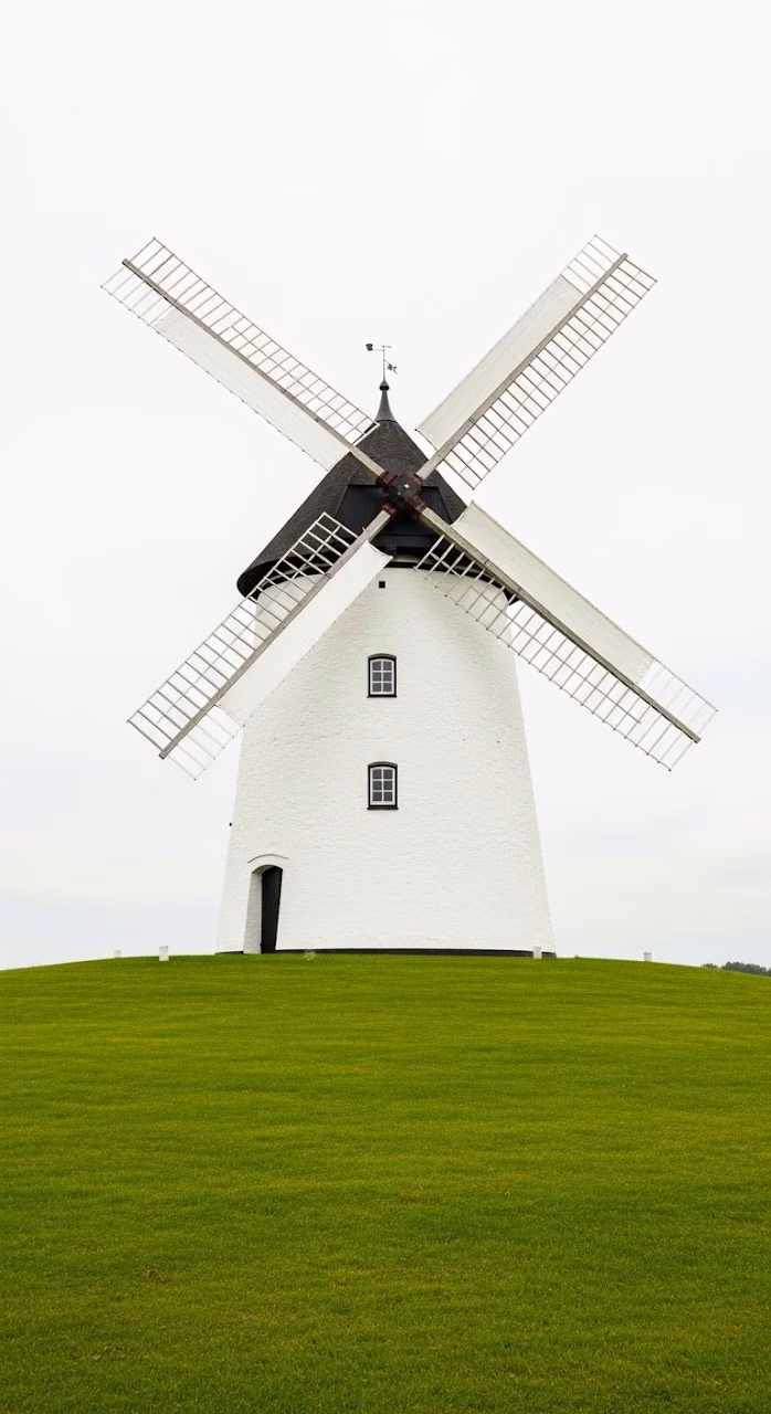 Traditional Historic Windmill in a Green Field Under an Overcast Sky - Free Mobile AMOLED Wallpaper Background