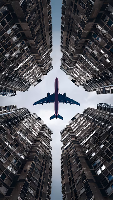 Airplane Flying Between Towering Skyscrapers from Below - Free 4K & 8K Mobile Wallpaper