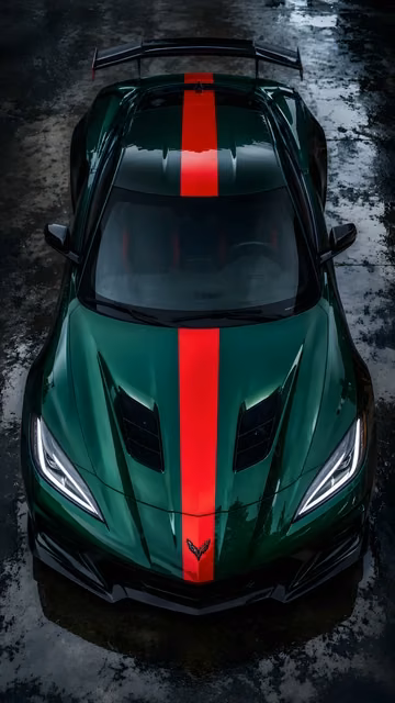 An overhead high-angle shot of a sleek forest green sports car with a wide red racing stripe parked on a wet asphalt surface.