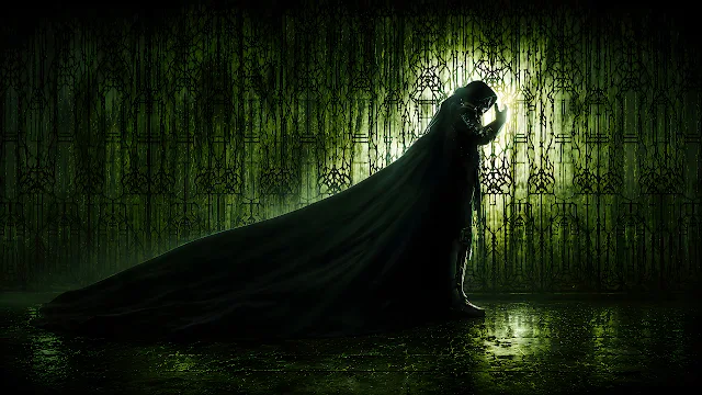 Doctor Doom stands in profile with a long dark cloak against an illuminated green patterned screen. Doctor Doom in profile wearing a long trailing cloak in front of a glowing green ornate wall.