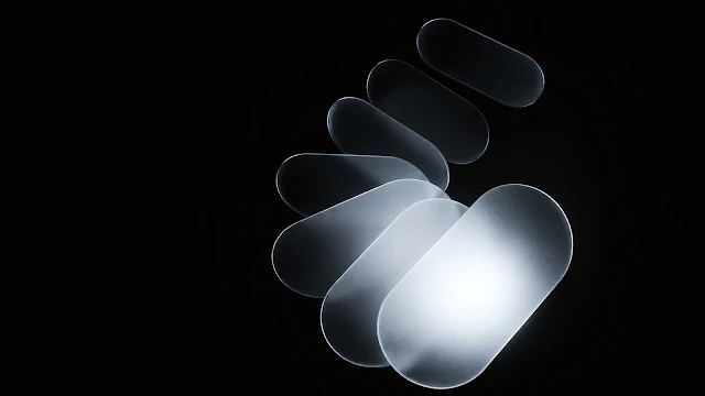 A curved spiral arrangement of frosted glass oval plates illuminated against black space. Overlapping frosted translucent glass oval shapes arranged in a spiral curve glowing softly on a black background.