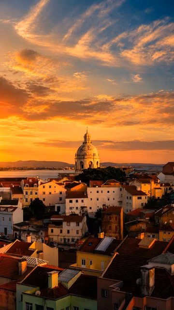 Historic domed building rises above dense terracotta rooftops beneath a glowing orange and blue evening sky.