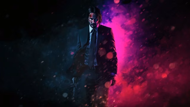 John Wick in a black suit walking forward through heavy rain illuminated by neon pink and cyan blue lights.