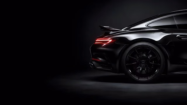 Glossy black high-end sports car rear quarter panel showcasing curved bodywork and a sleek red light bar against a dark gray backdrop.