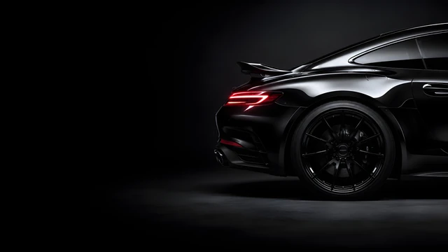Download Minimalist Black Sports Car Desktop Wallpaper Wallpaper in 4K UHD Glossy black high-end sports car rear quarter panel showcasing curved bodywork and a sleek red light bar against a dark gray backdrop.