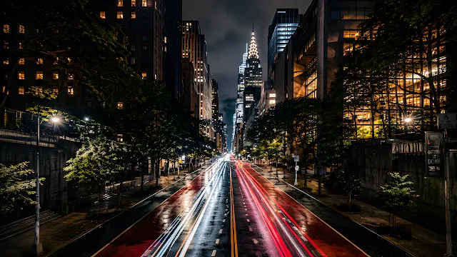 Traffic light trails along a New York City street leading toward the illuminated Chrysler Building. Long exposure photo of red and white car light trails on a New York City street facing the Chrysler Building.