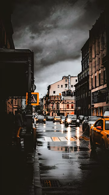 Rainy City Street Under Stormy Sky with Glowing Headlights - Free 4K & 8K Mobile Wallpaper