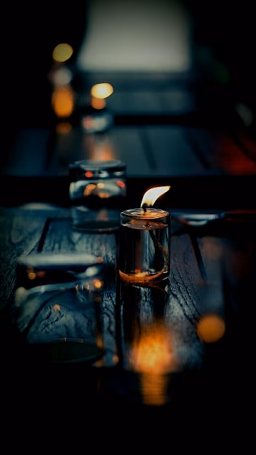 Single Candle Glowing on Dark Wooden Table - Free 4K & 8K Mobile Wallpaper