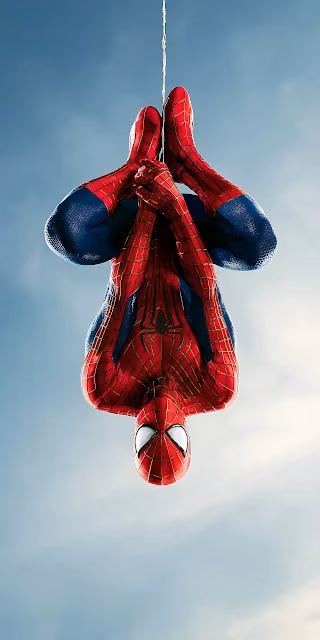 Spider-Man hangs inverted from a single web line against a clear open daylight sky. Spider-Man hanging upside down on a web line against a clear blue sky wearing a red and blue textured suit.