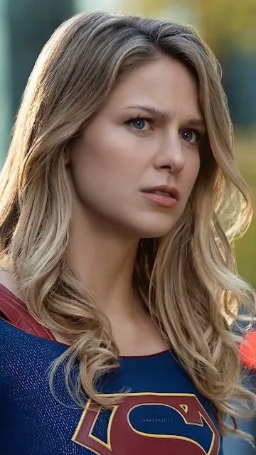 Close-up portrait of Kara Danvers in the Supergirl suit with blonde hair and a focused expression outdoors.