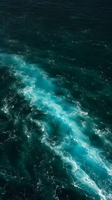 Turquoise ocean current cutting diagonally through deep emerald and black water.