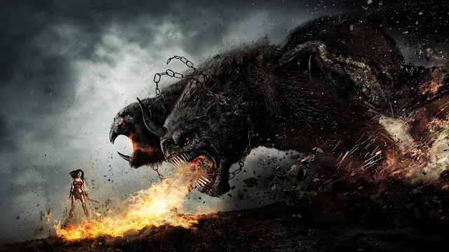 Wonder Woman faces a massive three-headed mythical beast unleashing flames across a dark rocky field. A giant two-headed hound breathing fire onto the ground in front of a small warrior woman standing in armor.